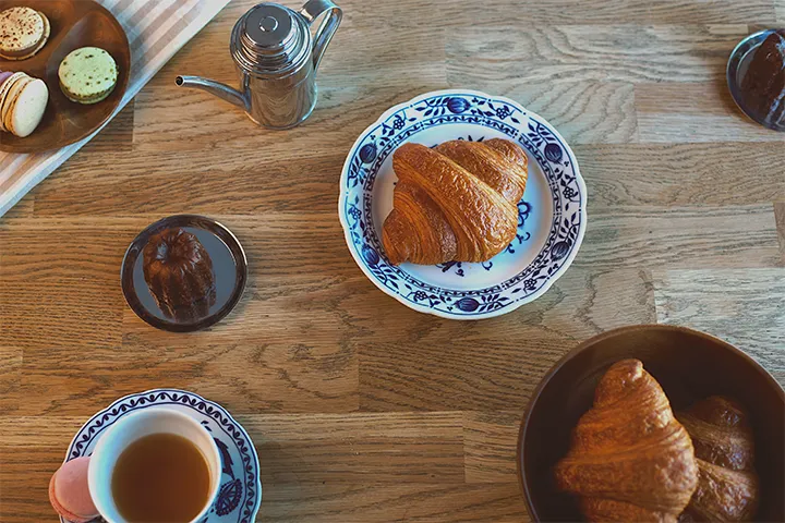 Croissanter, macarons och kaffe på ett träbord ovanifrån